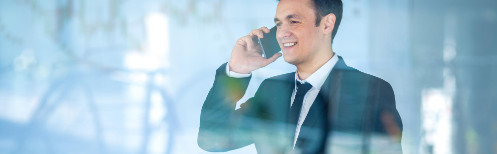 Happy man looking at phone by the window