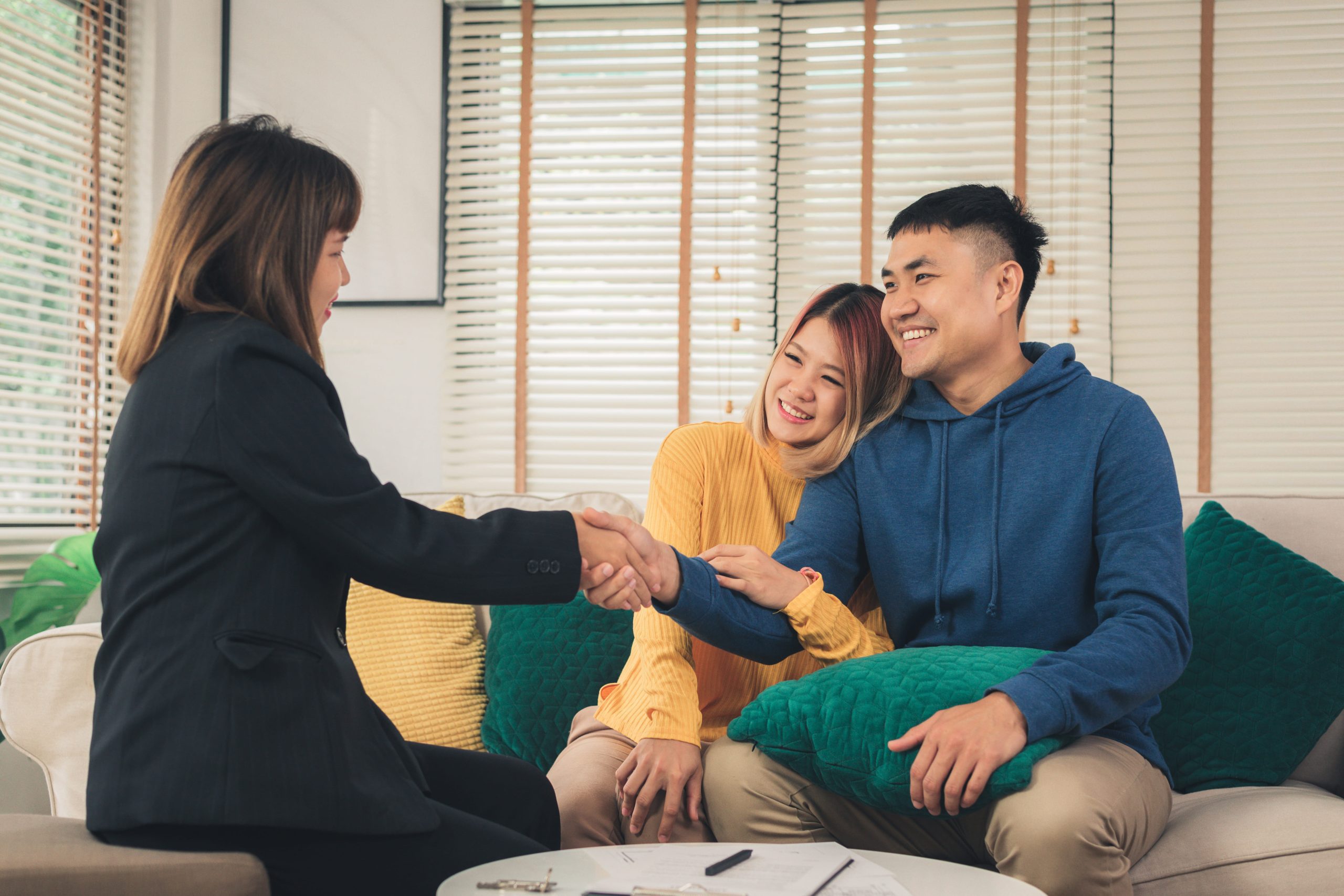 Happy young Asian couple and realtor agent