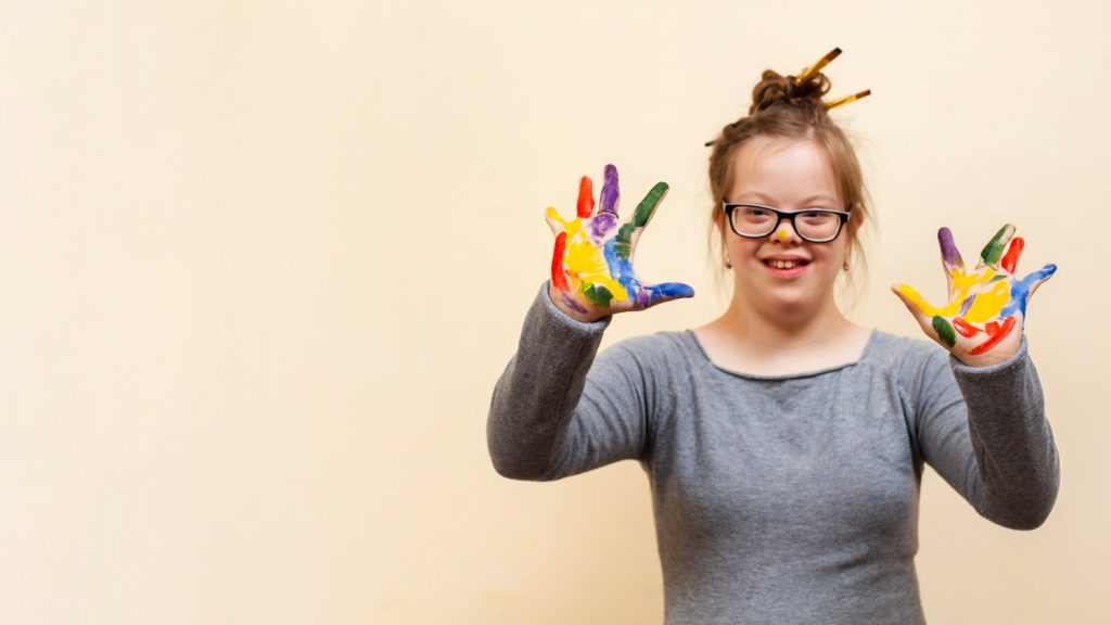 woman with Down syndrome with hands painted in various colors